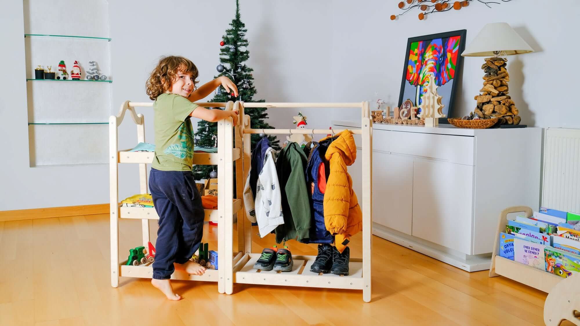 Child organizing clothes on a Montessori wooden clothes rack in a cozy, stylish room. Perfect for fostering independence!