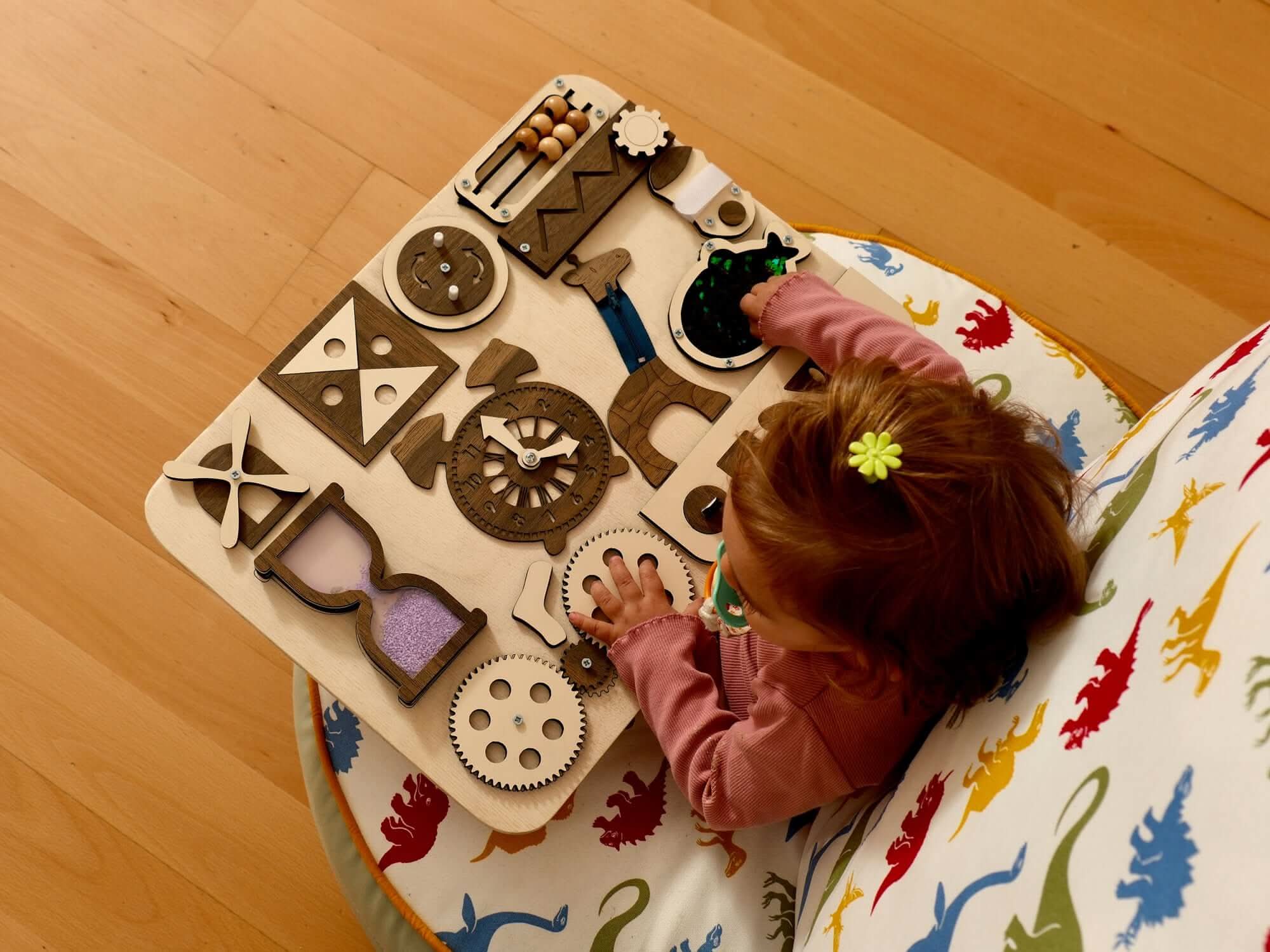 Toddler engaging with a wooden busy board featuring gears and tactile elements for hands-on learning.