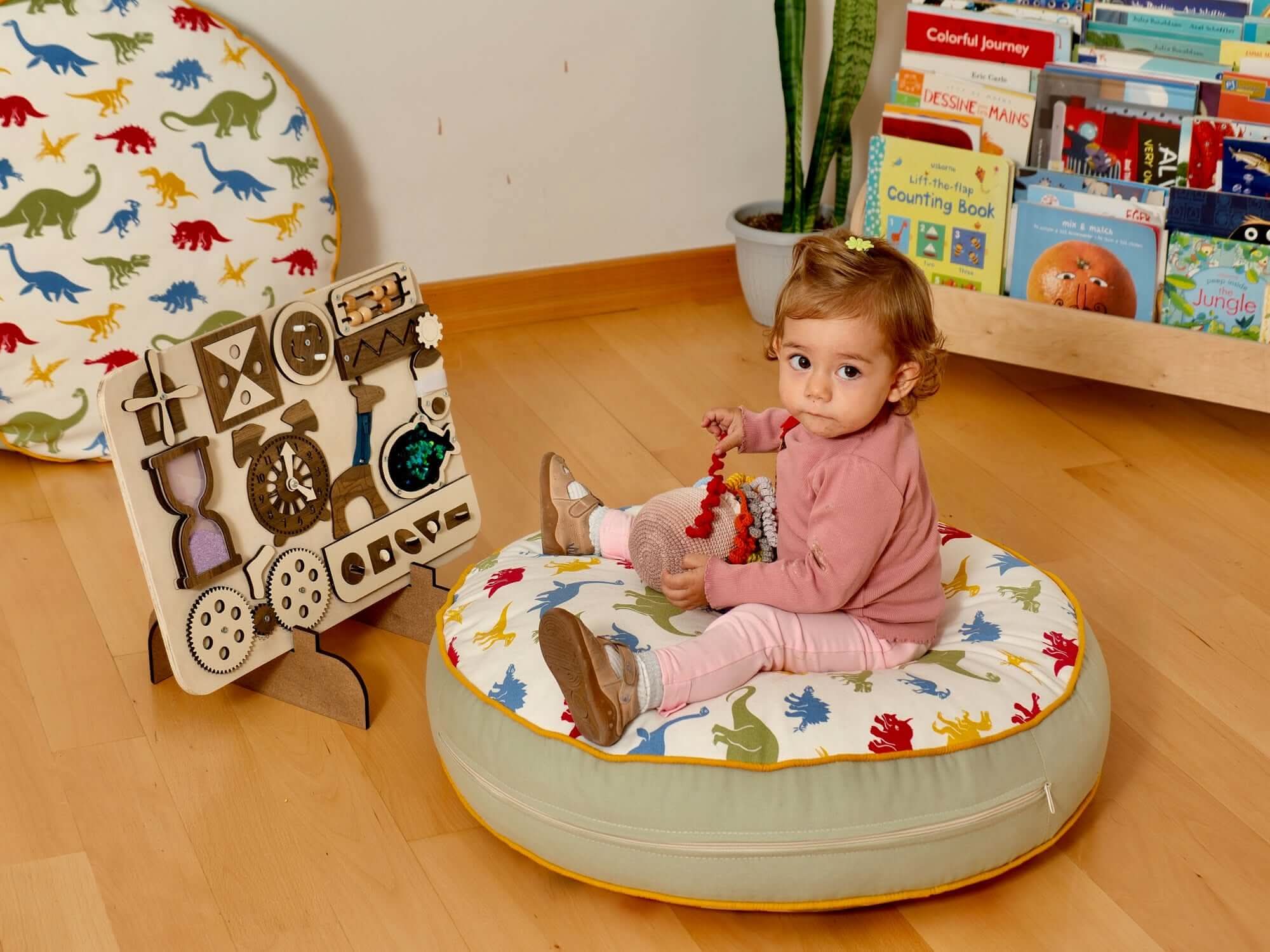 Toddler exploring a wooden busy board on a colorful cushion in a playful learning environment.