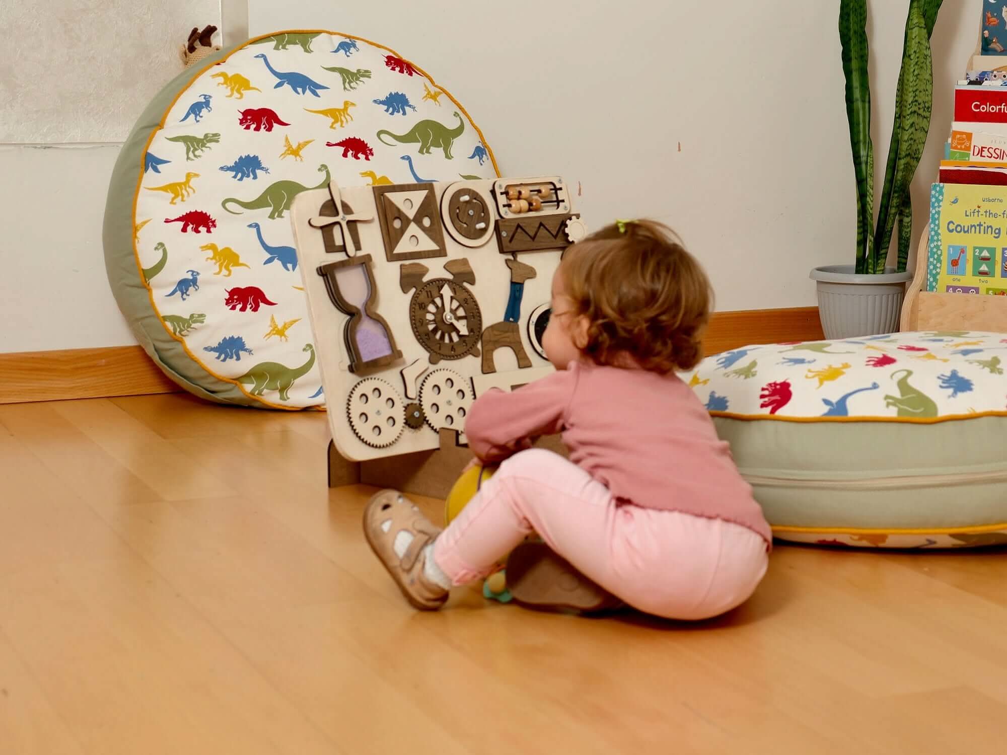 Toddler playing with a Wooden Busy Board, engaged in sensory learning activities in a playful environment.