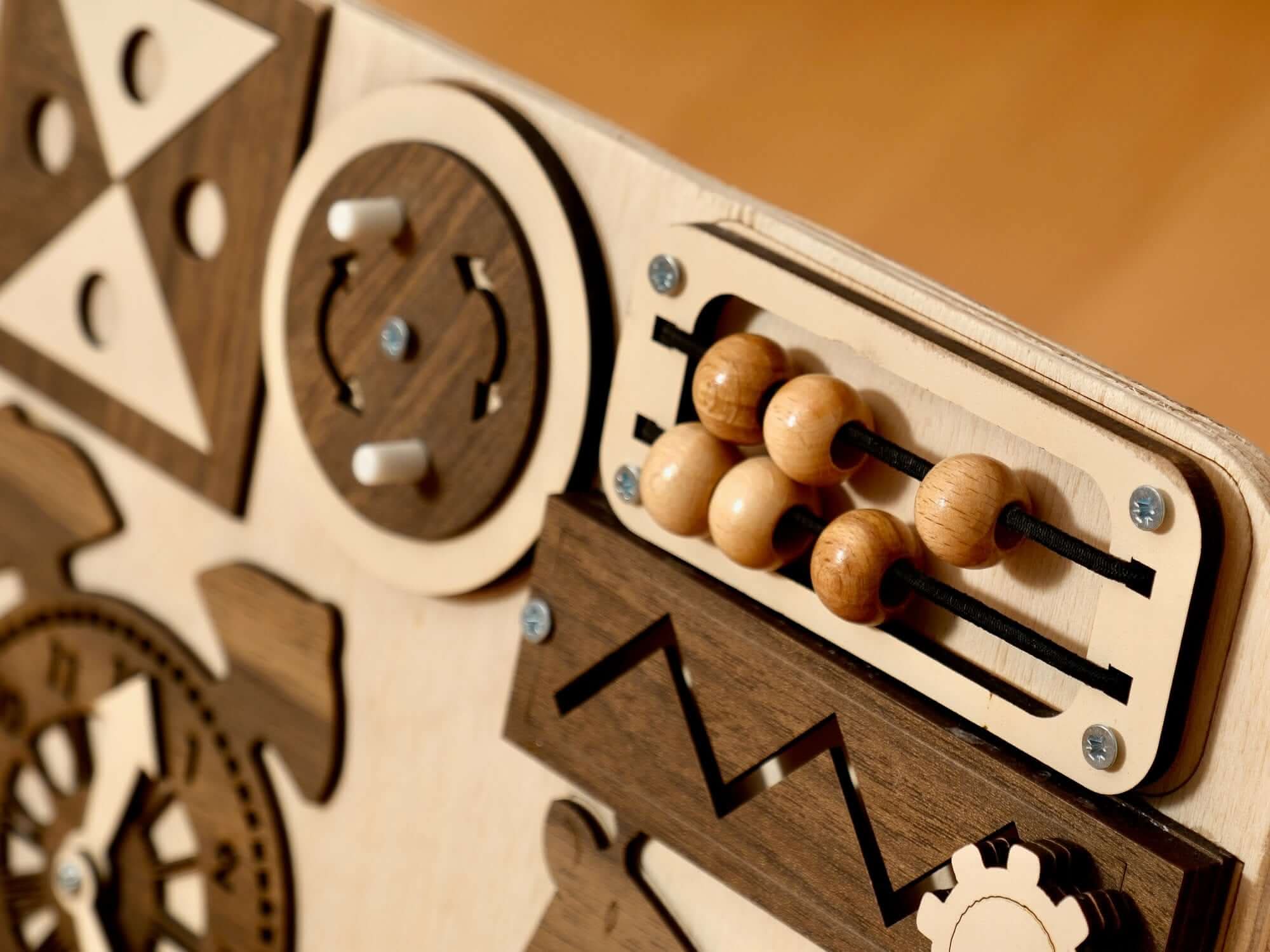 Close-up of a Wooden Busy Board for toddlers showcasing sensory activities like an abacus and gears.
