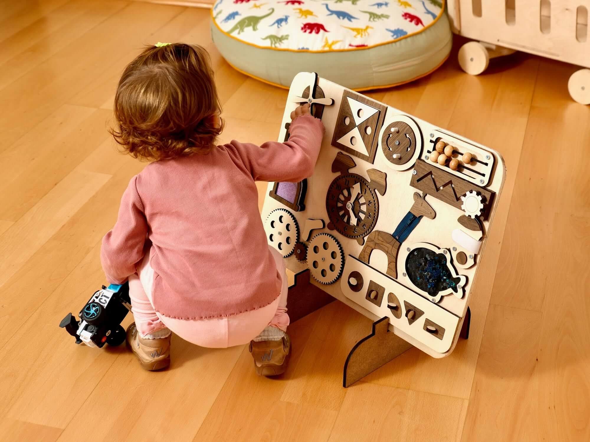 Toddler interacting with a Montessori-inspired Wooden Busy Board, exploring gears, shapes, and tactile elements.