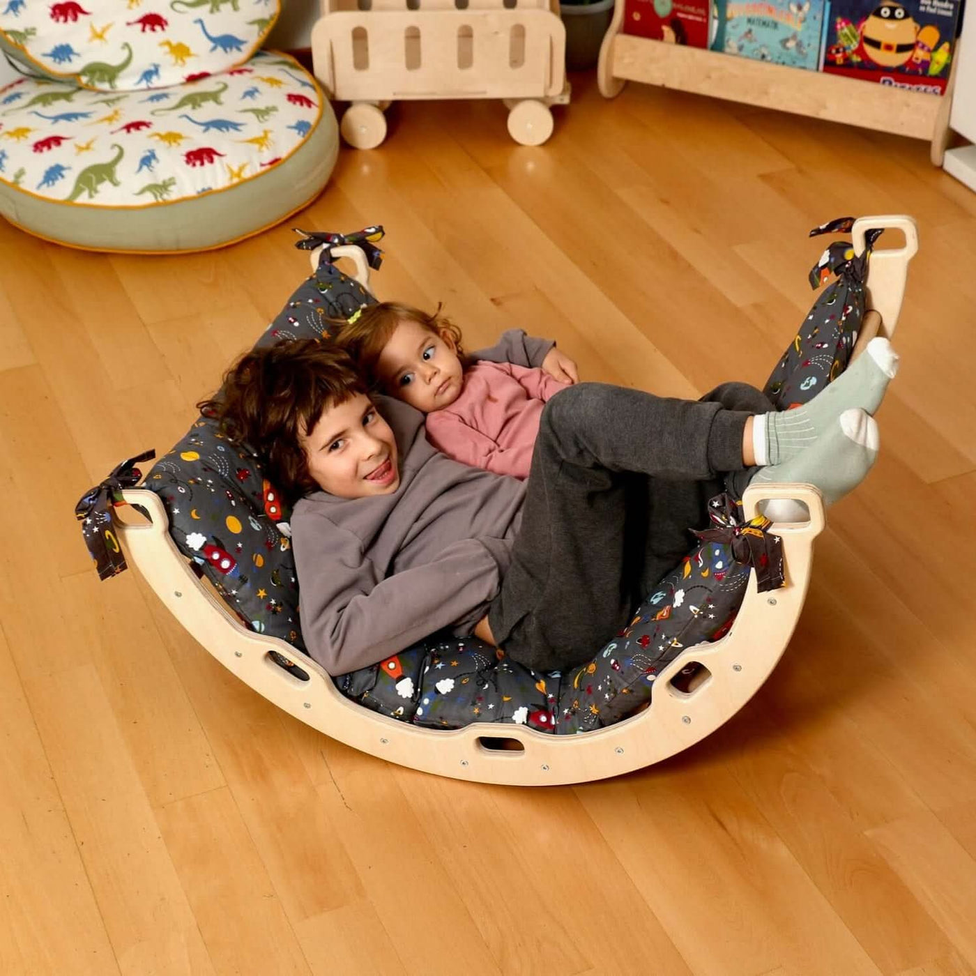 Two children enjoying playtime on a cozy Montessori climbing arch rocker with pillows, enhancing their motor skills.
