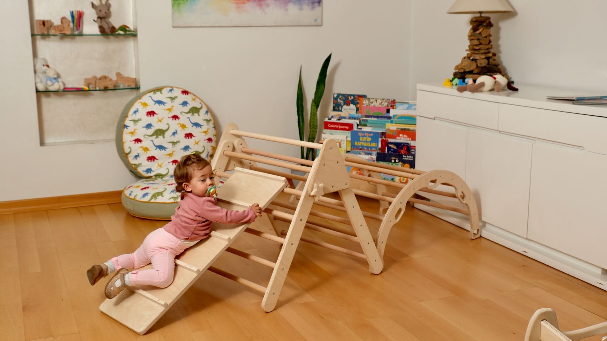 Toddler playing on a Montessori climbing set with a Pikler triangle and slide, enhancing indoor play and learning.