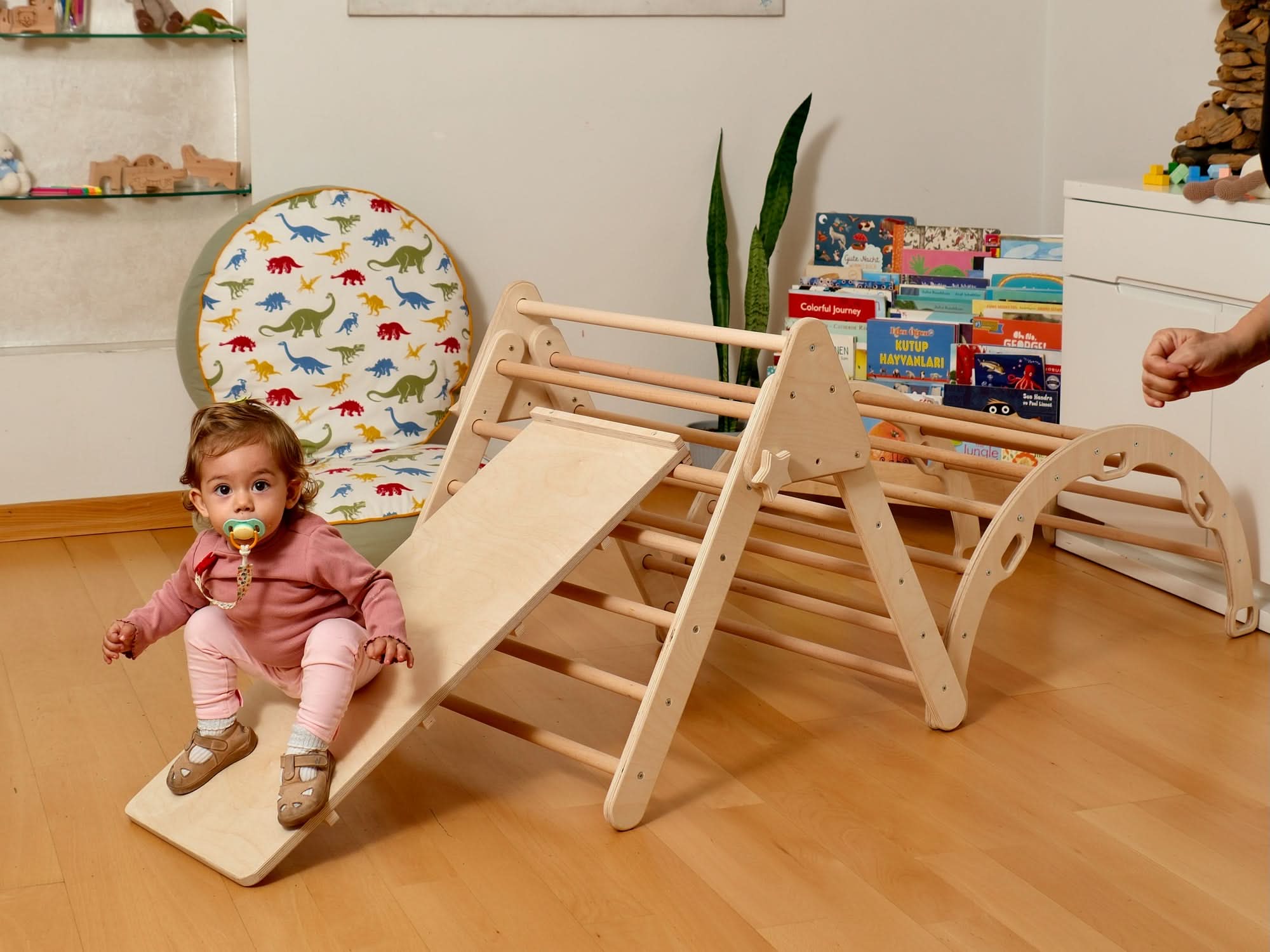 Toddler enjoying a Montessori indoor playground with climbing arch and slide, perfect for play and learning.