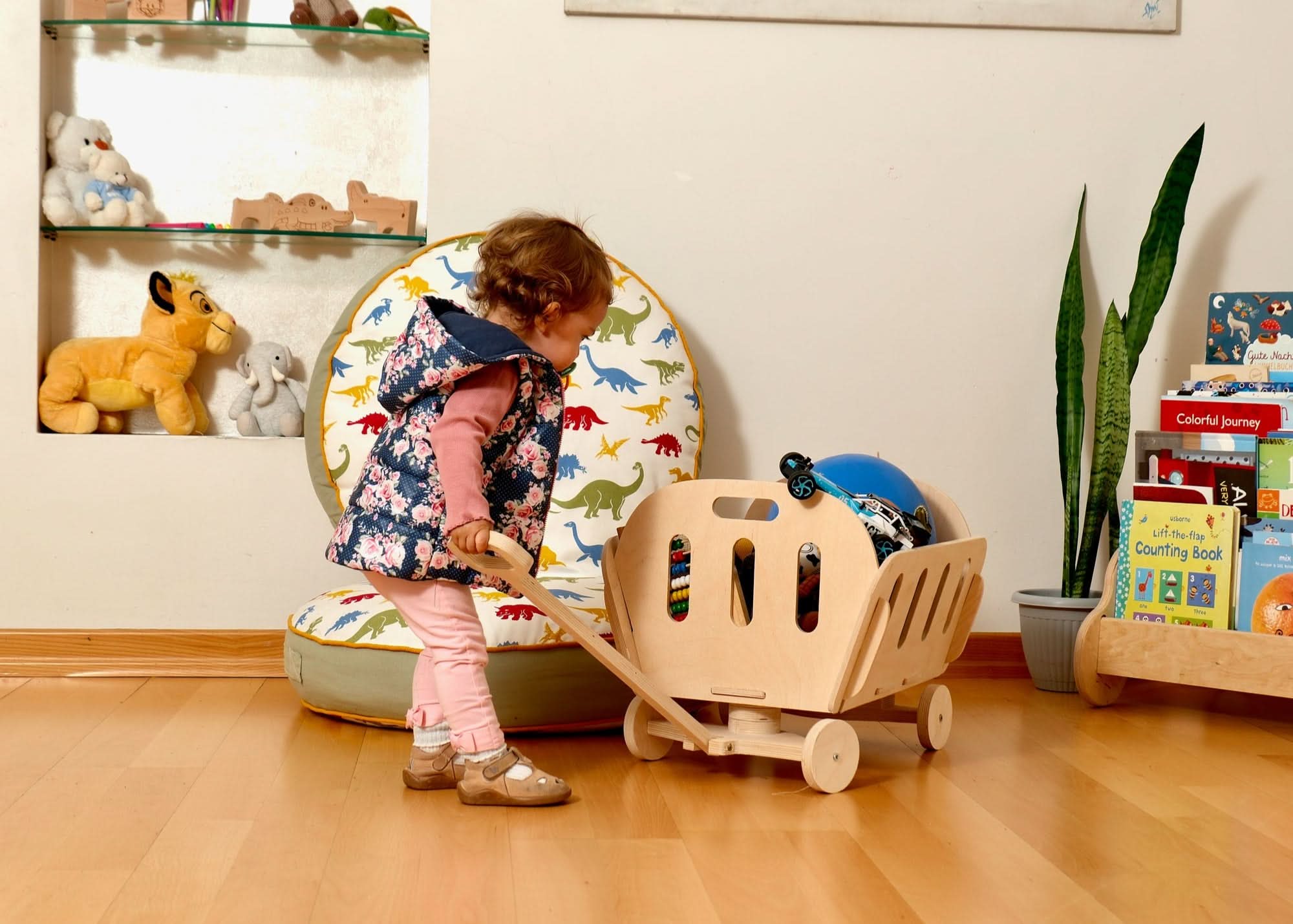 Toddler using a Montessori wooden toy storage cart, promoting play and organization in a colorful nursery.