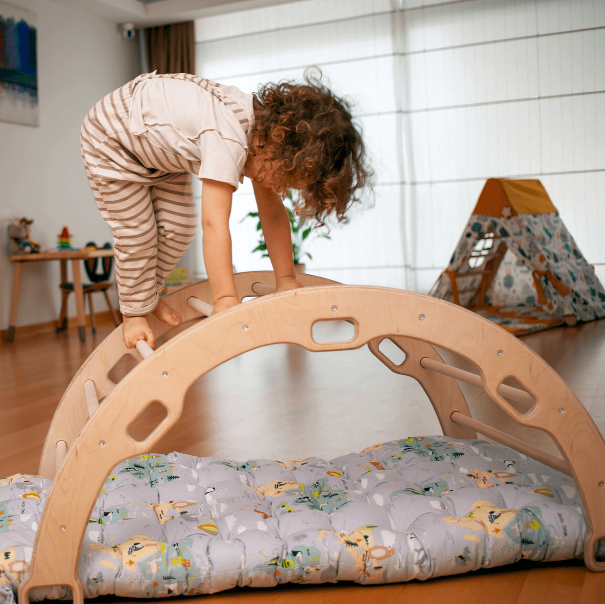 Child climbing the original Kidodido wooden arch in a sunlit playroom